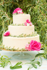 Beautiful wedding cake with flowers on table, outdoors. Three levels