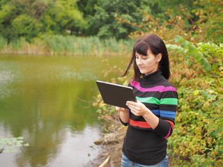 Obraz premium Beautiful young woman using tablet pc at autumn park. Pretty you