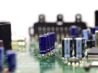 four electrolytic capacitors mounted on printed circuit board in a row, shallow depth of field