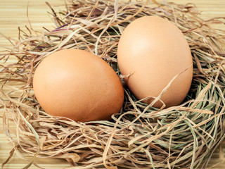 Closeup brown chicken eggs in a straw nest . Fresh organic eggs