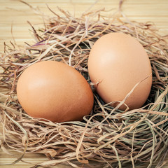 Closeup brown chicken eggs in a straw nest . Fresh organic eggs