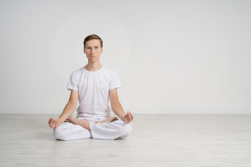 Young man meditating in Lotus position on the floor