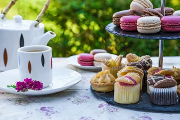 Selbstklebende Fototapeten Tea with cakes and macaroons set up in the garden © beataaldridge