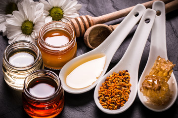 Honey in jar with honey dipper on black stone background