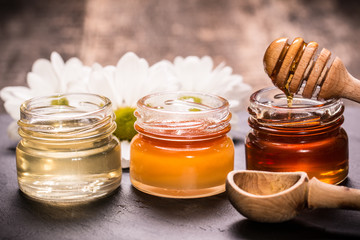 Honey in jar with honey dipper on black stone background