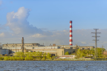 Obraz premium metallurgical plant near pond on a background of blue sky