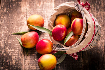 Fresh peaches in a basket on rustic wooden table.