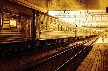 Fototapeta na wymiar Train at railway station, sunset orange light