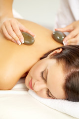 Young woman being massaged at spa salon with stones