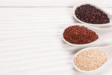 Obraz na płótnie Canvas Red, black and white quinoa seeds on a wooden background