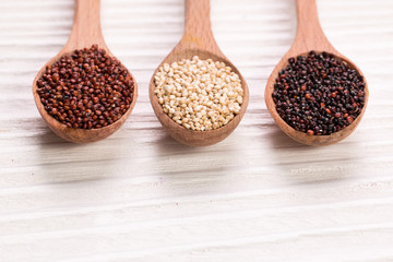 Red, black and white quinoa seeds on a wooden background