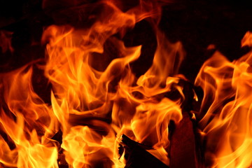 Closeup of a large fire. Wooden planks to the fire. The fire is lit in the night.