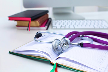 Stethoscope lying on a notebook computer in the background and books