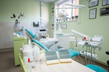 Set of different dental burs and supplies on the stand near dental unit in a modern dental office