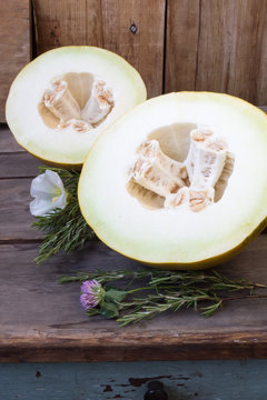Sliced melon with a rosemary on rustic wooden background, vertic