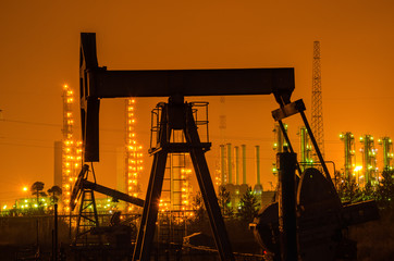 Oil rig silhouette at the background of refinery by night. Oil and gas industry. 