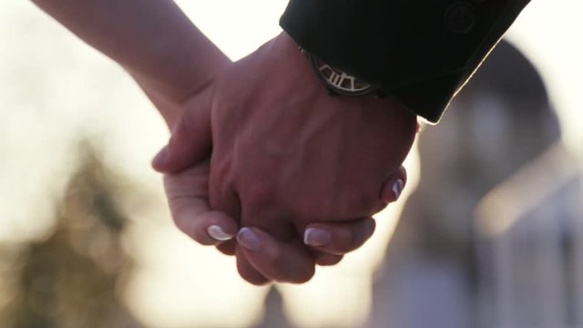 A close up view of joining just married wife and husband hands, holding hands. Happy moments. No people around. Outside shooting, hands on bright sunlight background. Wedding, love atmosphere.