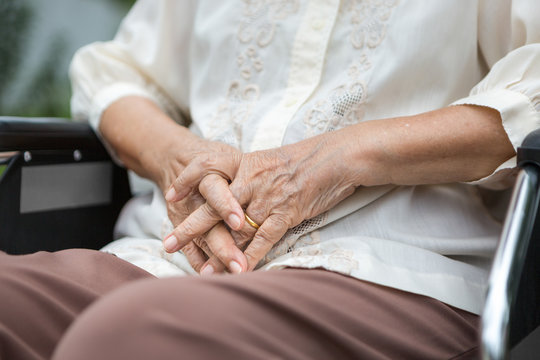 Elderly hands on a wheelchair.