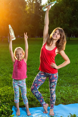 Obraz premium Mother and her daughter outdoors doing yoga