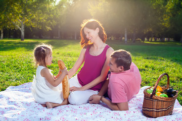 Happy young family having picnic at meadow