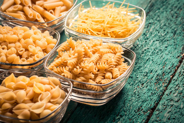 Various mix of pasta on wooden rustic background. Diet and food