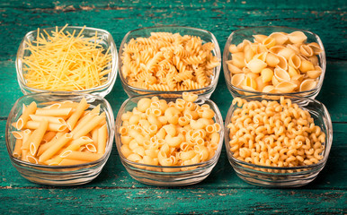 Various mix of pasta on wooden rustic background. Diet and food