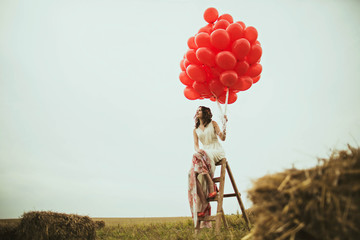 woman holds many big  red balloons