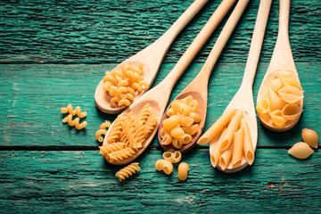 Various mix of pasta on wooden rustic background. Diet and food