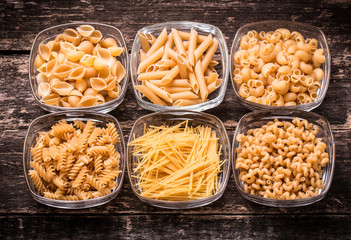 Various mix of pasta on wooden rustic background. Diet and food