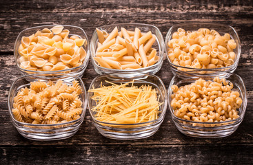 Various mix of pasta on wooden rustic background. Diet and food
