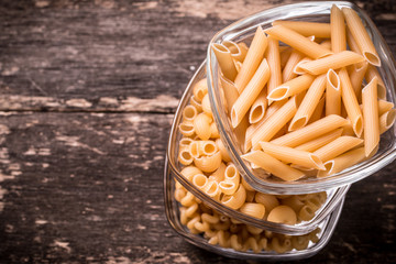 Various mix of pasta on wooden rustic background. Diet and food