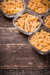Various mix of pasta on wooden rustic background. Diet and food