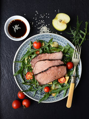 salad of arugula and roast beef on a black background