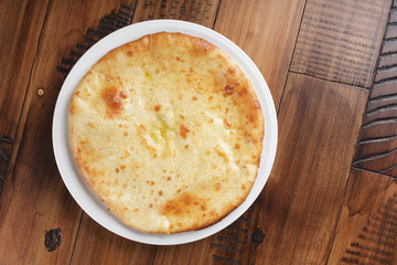Ossetian pie with potatoes or mutton on a white plate. Wooden background.