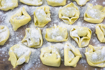 Row of raviolis in flour on the wooden table
