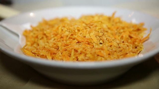 carote alla julienne impanate e fritte con olio di oliva disposte su un piatto bianco ad un buffet di una festa