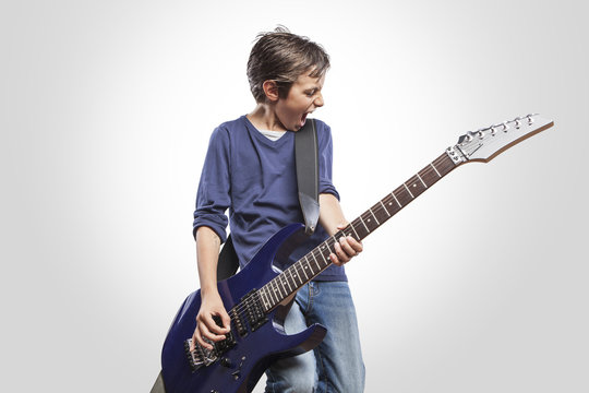 Portrait of adorable young boy playing electric guitar. Rock and