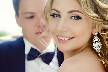 Wedding couple on the nature is hugging each other. Beautiful model girl in white dress. Man in suit. Beauty bride with groom. Female and male portrait. Woman with lace veil. Lady and guy outdoors