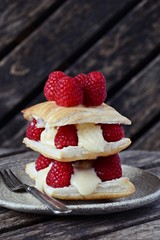 Millefeuille dessert with raspberry on the dark background, french dessert on the plate
