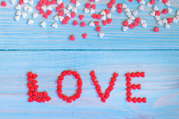 Red candy hearts laying on light blue painted rustic wooden background