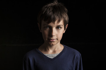 Portrait of adorable young happy boy on dark background