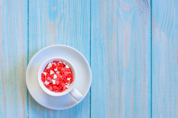 Coffee cup full of candies flat lay on rustic light blue wooden background