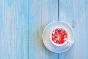 Coffee cup full of candies flat lay on rustic light blue wooden background