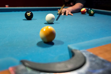 young man playing pool in a bar (focus on the white ball)
