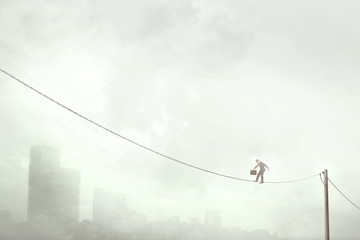 business man balancing on a electric wire over the city