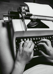 Mujer joven escribiendo en una máquina de escribir antigua 