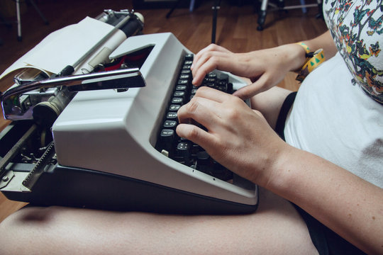 Mujer joven escribiendo en una máquina de escribir antigua 
