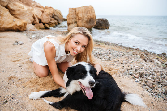 Cheerful woman hugging her dog on the beach
