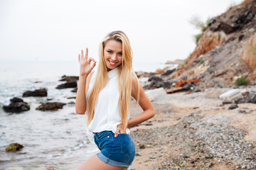 Beautiful woman showing ok sign on the beach