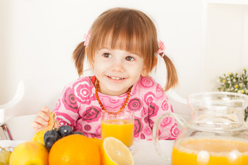 Mischievous little girl smiling. Fruit and orange juice for breakfast.